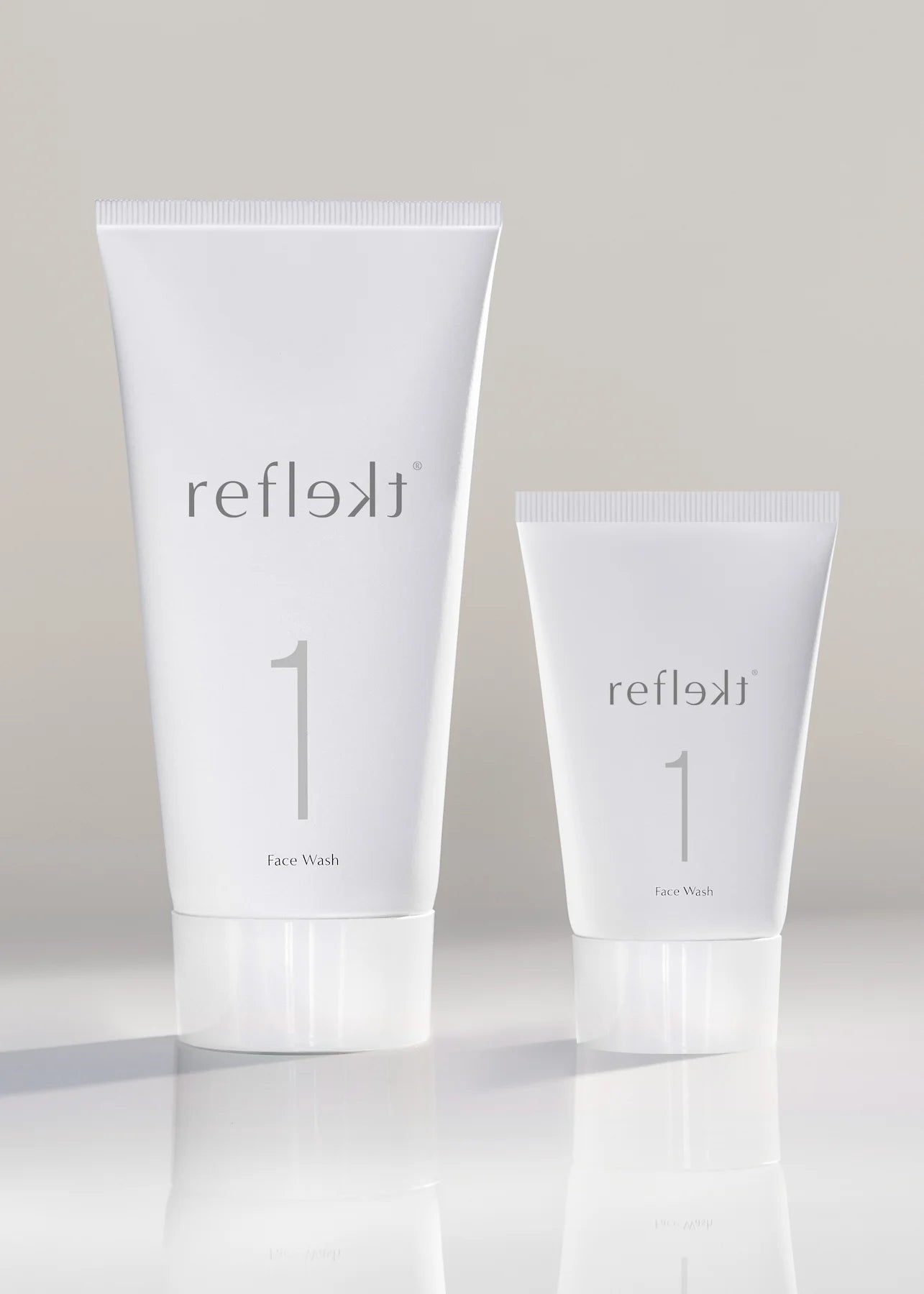 Two white tubes of reflekt skincare product on a light gray background