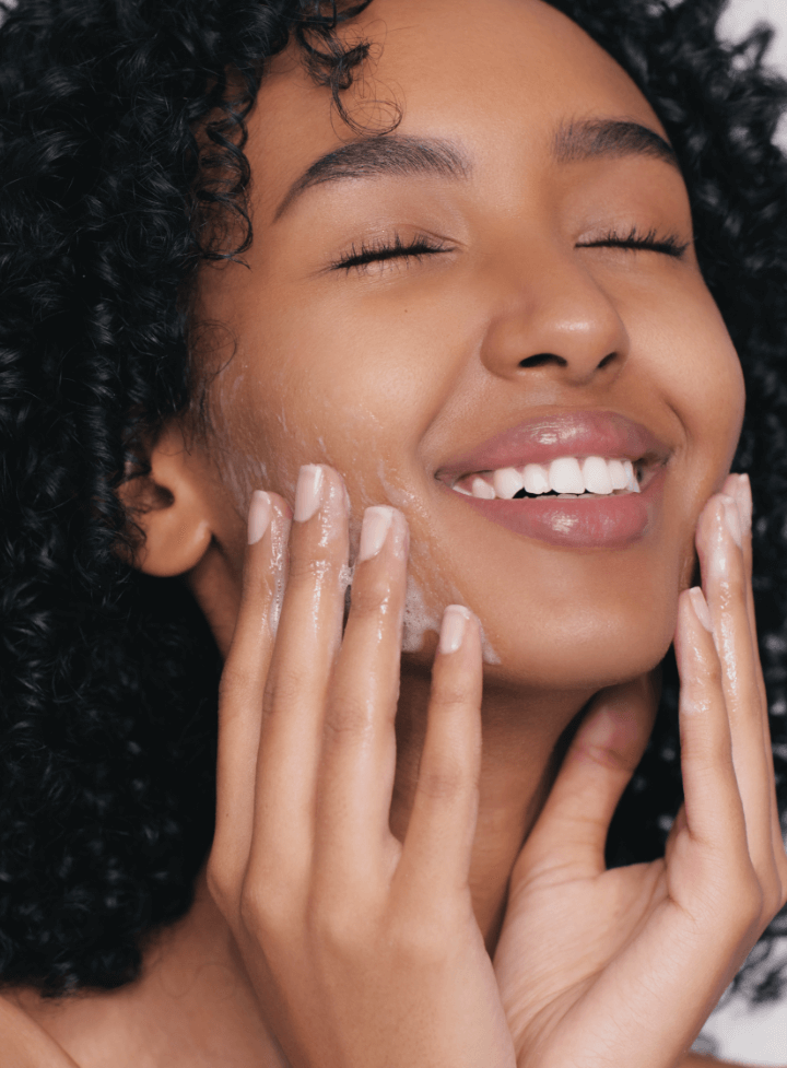 Woman applying Reflekt 1 Daily Exfoliating Face Wash to damp skin, showcasing gentle exfoliation