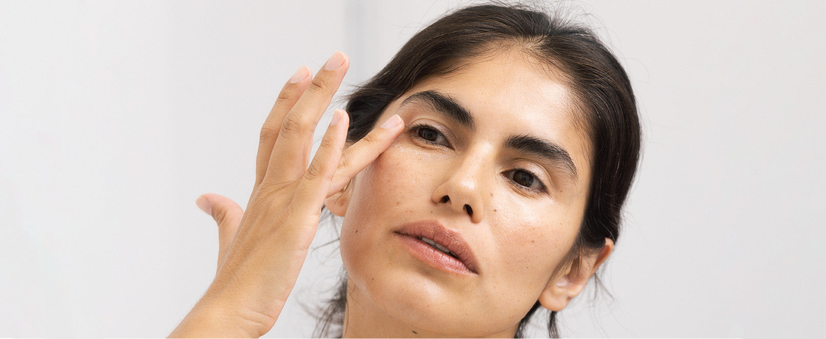 A woman gently applying the Smoothing Eye Cream to her under-eye area with her fingers